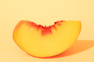 Juicy slice of peach on yellow background