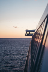 Bridge wing and the side windows reflecting the sun as it is going down at sea. Finland