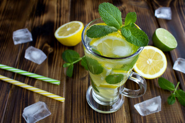 Cold  lemonade with lemon and mint  in the glass on the brown wooden background.Closeup.