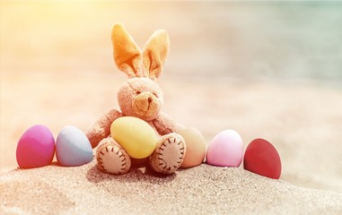Easter bunny and color eggs on beach sand