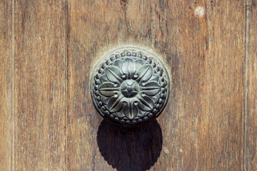 Medieval iron handle with floral design on an old weathered wooden door