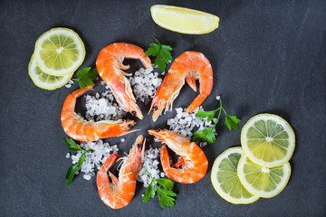 boiled shrimps with salt and lemon are beautiful against a dark background, top view
