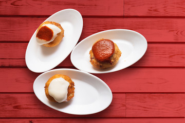 patatas bravas stuffed with meat with spicy sauces on red wood