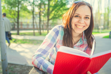 Woman with a book in his hands in the Park. Female, student is reading an interesting book sitting on the bench in the park