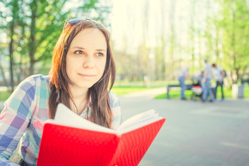 Woman with a book in his hands in the Park. Female, student is reading an interesting book sitting on the bench in the park