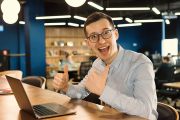 Business man in glasses with thumbs up at the office