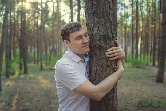 Man hugging tree in the forest. Smiling young male nature lover relax on summer day hug a tree enjoy in beautiful day	