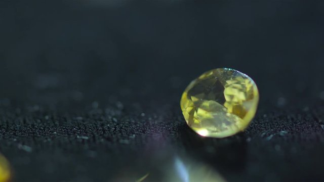 Macro shot of precious gems diamonds and zircons made with a Red camera on slow motion falling on a black background inside a jewelry workshop