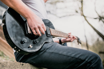 Technique of playing the electric guitar - a man playing outdoors - heavy hard rock and blues music