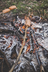 Cooking fried sausages on a fire in the forest