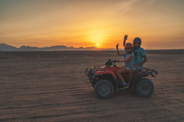 Family travels at sunset in the desert on an ATV © Alex Tor