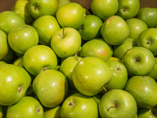 Many green delicious apples in a box in the store