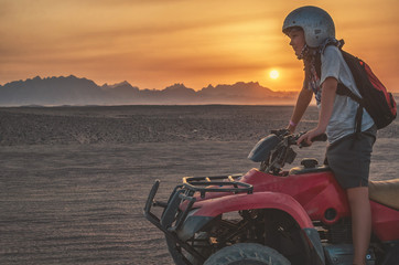 Boy travels on an quad bike in the desert at sunset © Alex Tor