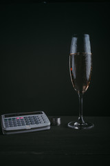 Glass of champagne against a dark background with coins and calculator. concept of financial victory or success