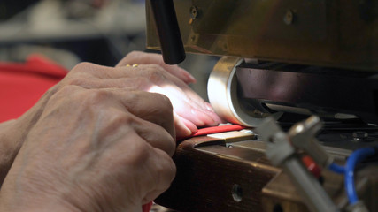 In a slow motion video in a garment factory, women press (cut) various pieces of clothing and fabric locks and various materials using different machines. Concept of: Work, Factory, Seamstress.