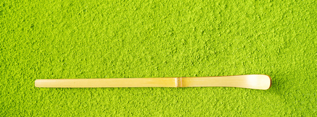 Top view of bamboo Chashaku spoon on powdered Green Matcha tea background with copy space. Long...