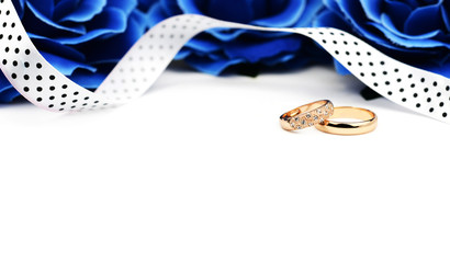 gold wedding engagement rings with white ribbons lace blue flowers on a white background