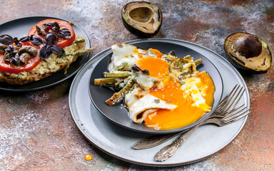 Tasty breakfast. Sandwich with tomatoes and mushrooms, avocado, fried eggs with asparagus.