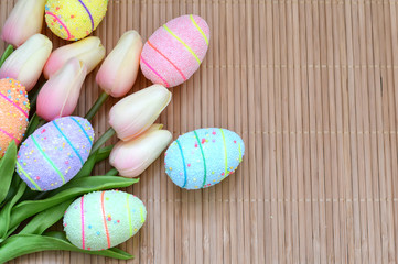 Easter card. Hand-made Easter eggs with a bouquet of pink tulips on a wooden surface. Space for text.