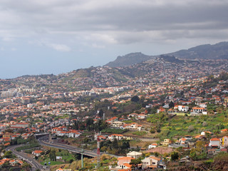 Fototapeta na wymiar a view of funchal from above showing the city and hills with ocean and blue sky in the distance