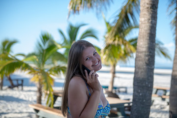 Young woman with smartphone in front of the palm