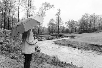 Woman in the rain viewing a stream in Arkansas in black and white