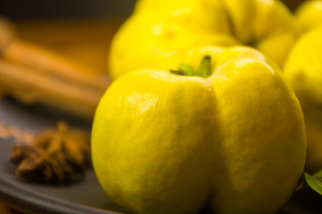 large yellow quince fruits on a ceramic plate, with anise, cinnamon, and walnuts