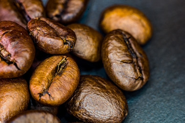 Brown roasted coffee beans on black background, close up, macro