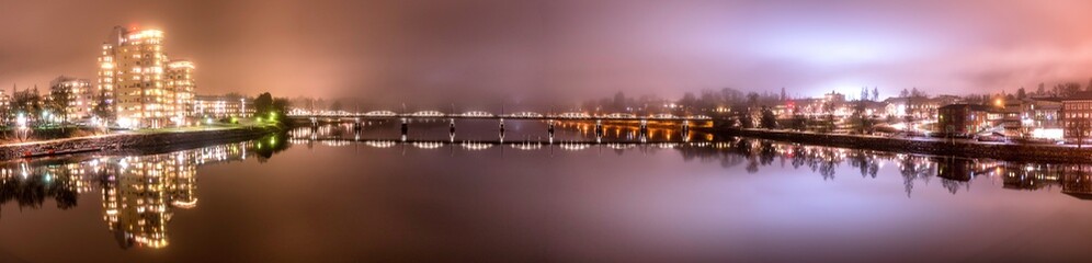 Panorama, foggy view from the central bridge over the river to the both sides of Umea city with pedestrian bridge in the middle, Vasterbotten municipality, Sweden