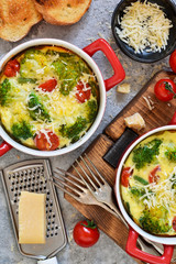 Casserole with broccoli, tomatoes and parmesan on a concrete background. View from above.