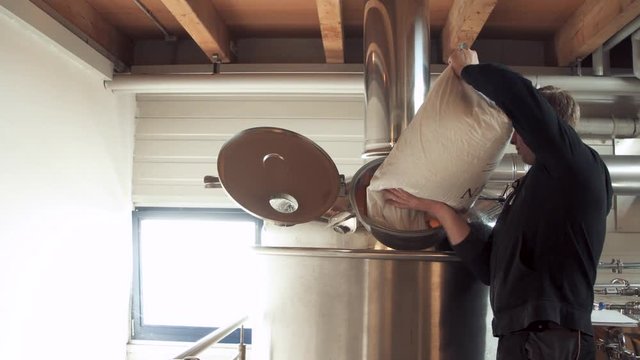 craftbeer brewer pouring malt into brewing kettle
