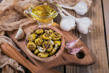 Grilled olives with garlic, olive oil and spices on rustic wooden table