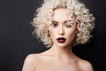 Sexy naked girl with full lips and with wonderful blue eyes, with blond curly hair and professional bright makeup, isolate at black background