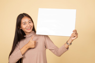 Obraz na płótnie Canvas Young Asian woman show thumbs up with white blank sign.
