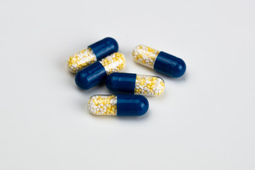 Blue and yellow capsules on light grey background