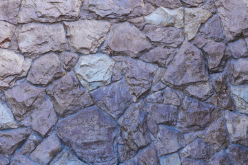 Photo of a fragment of a wall of uncrushed rough stone covered with varnish