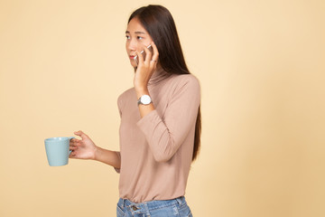 Young Asian woman with mobile phone and coffee cup.