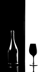 Black champagne bottle with black champagne glass isolated on black and white background
