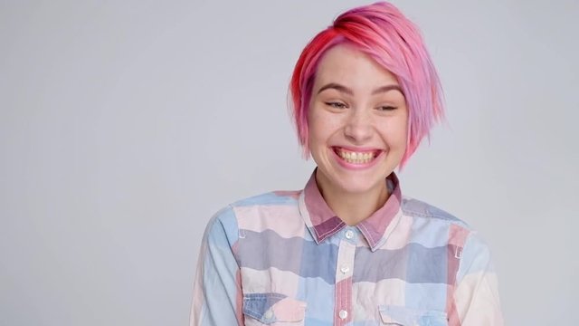 Young beautiful girl with a short hair cut pixie bob. Color hair coloring, red pink color. Shirt in a cellar, casual style, white background.