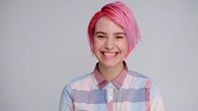 Young beautiful girl with a short hair cut pixie bob. Color hair coloring, red pink color. Shirt in a cellar, casual style, white background.