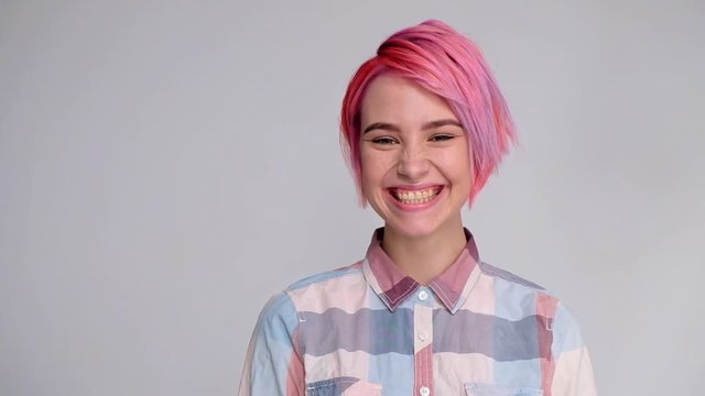 Young beautiful girl with a short hair cut pixie bob. Color hair coloring, red pink color. Shirt in a cellar, casual style, white background.