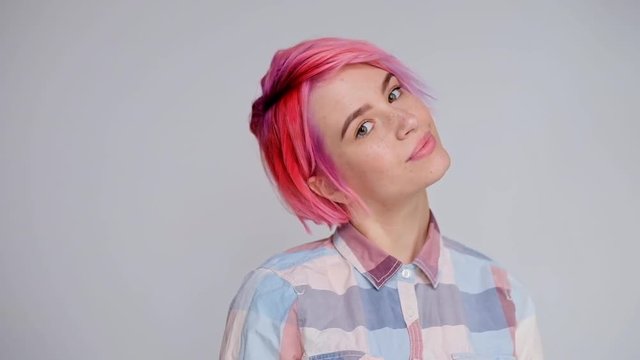 Young beautiful girl with a short hair cut pixie bob. Color hair coloring, red pink color. Shirt in a cellar, casual style, white background.
