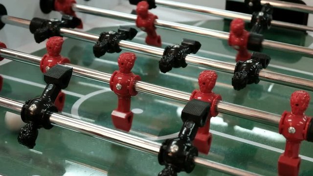 Table football soccer game kicker with red and blue players. Close-up. Young friends playing table football together indoors