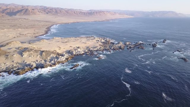 Las Tortolas beach aerial footage at Atacama Desert the sunset ray lights illuminate this amazing and idyllic beach in the middle of the desert, an arid awe landscape crashed by Pacific Ocean waters