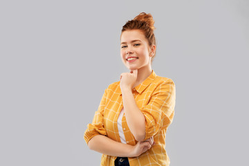 people concept - smiling red haired teenage girl in checkered shirt over grey background