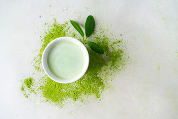 Close view of bawl with Japanese Matcha tea over scattered  powder tea on concrete background with copy space, top view.