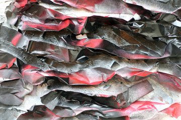 Painted crumpled pieces of paper on the surface of a rough wall. Red black tones