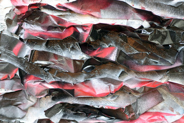 Painted crumpled pieces of paper on the surface of a rough wall. Red black tones