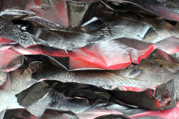 Painted crumpled pieces of paper on the surface of a rough wall. Red black tones