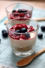 Simple no-bake raspberry cheesecake in a glass. Decorated with blueberries. Selective focus.
